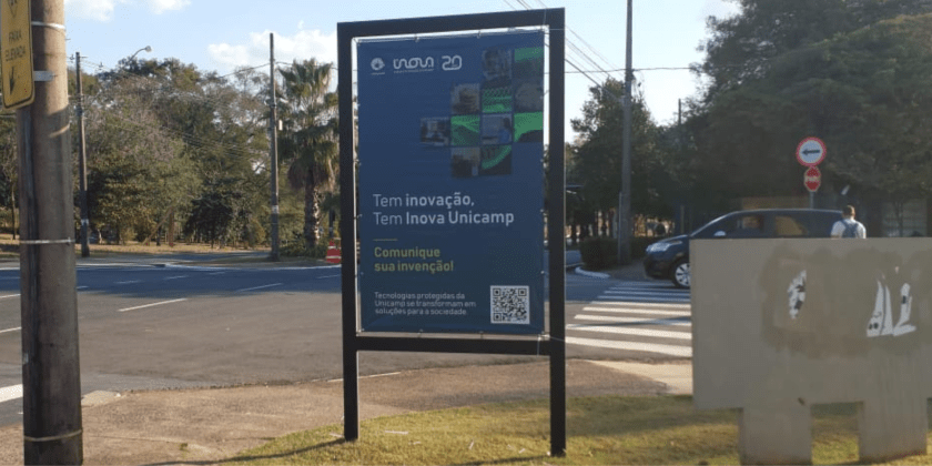 Foto externa mostra banner da campanha de proteção da propriedade intelectual da Unicamp na esquina da rua Monteiro Lobato com a Avenida Albert Einstein, na Unicamp. Fim da descrição.